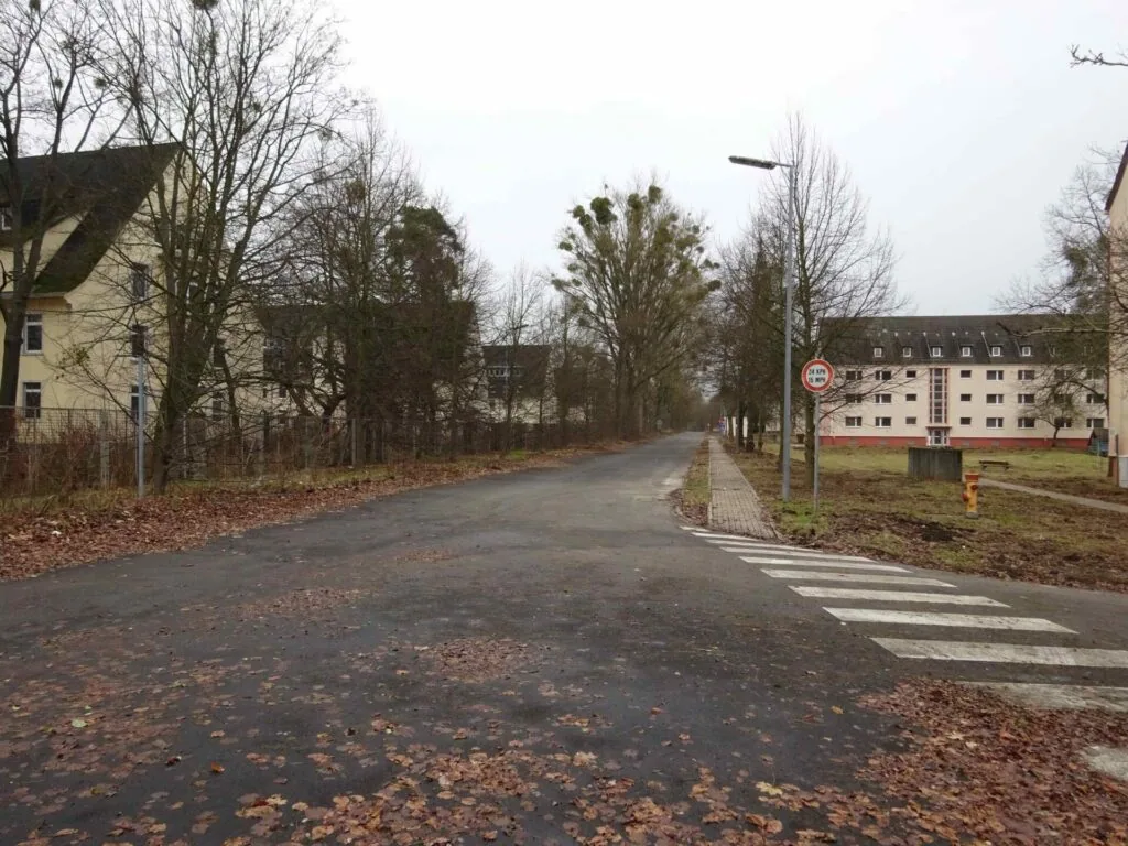 Residential street in winter with bare trees, apartment buildings, and a crosswalk marked with white stripes